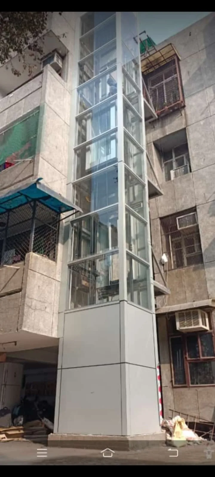 External glass elevator shaft retrofit fitted between two residential blocks