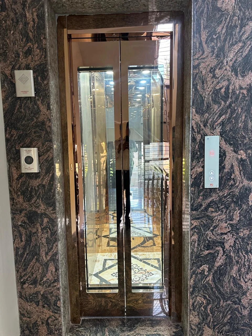 Mirrored elevator entrance in a marble-clad residential lobby