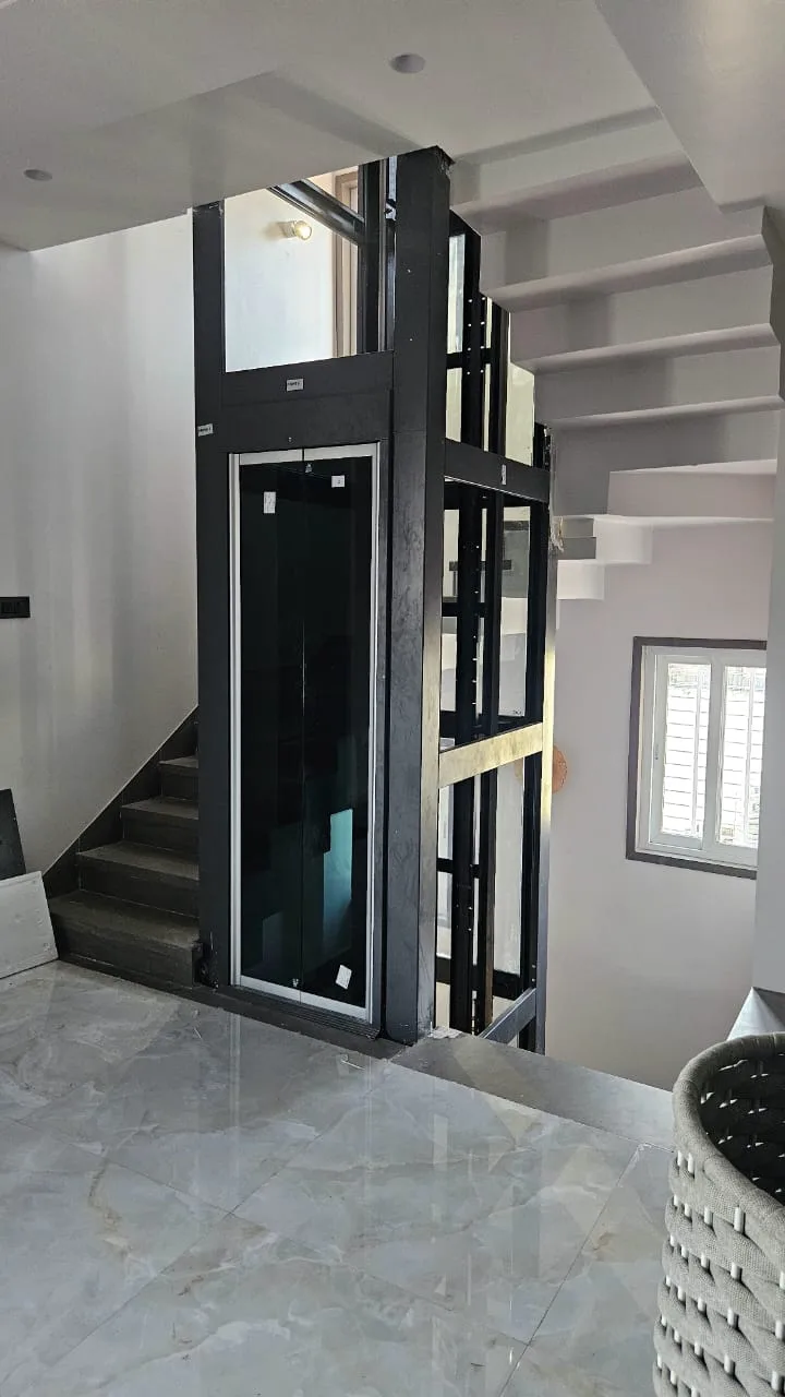 Glass home elevator installed beside a staircase in a modern duplex